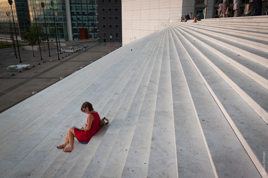 People sit on the steps of the Grande Arche in Paris